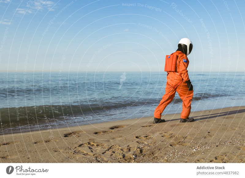 Spaceman walking and admiring sea spaceman beach astronaut admire evening stroll rest concept futuristic resort sand vacation stand spacesuit helmet cosmonaut