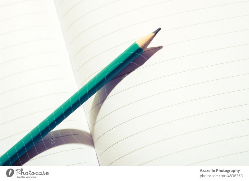 Aqua blue pencil on an open notebook. Close up image of a pencil on white paper. blank close up macro minimalism abstract bright business college concept