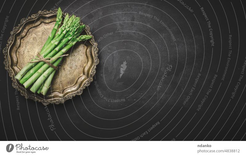 Fresh green asparagus sprouts on a round copper plate, black background. View from above nutrition bunch bundle closeup cook cookery cooking diet epicure food