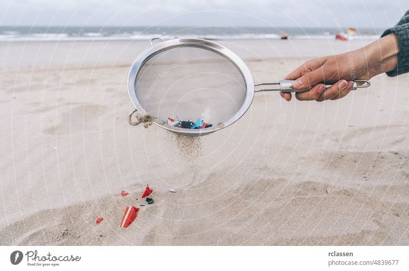 Young woman cleaning microplastics from sand on the beach, Environmental problem, pollution, ecolosystem and climate change warning concept hand marine europe