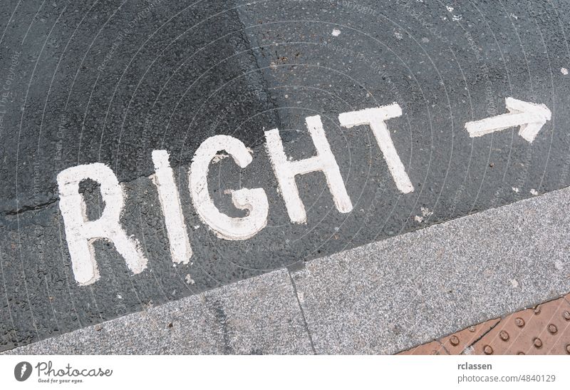 right warning sign with arrow in a London street city asphalt attention background britain british careful carefully caution concept conceptual concrete