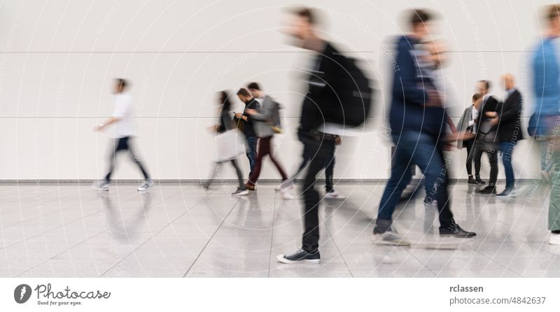 Anonymous blurred group of business people at a trade fair or convention shopping center mall advertising poster mock-up event conference advertising space