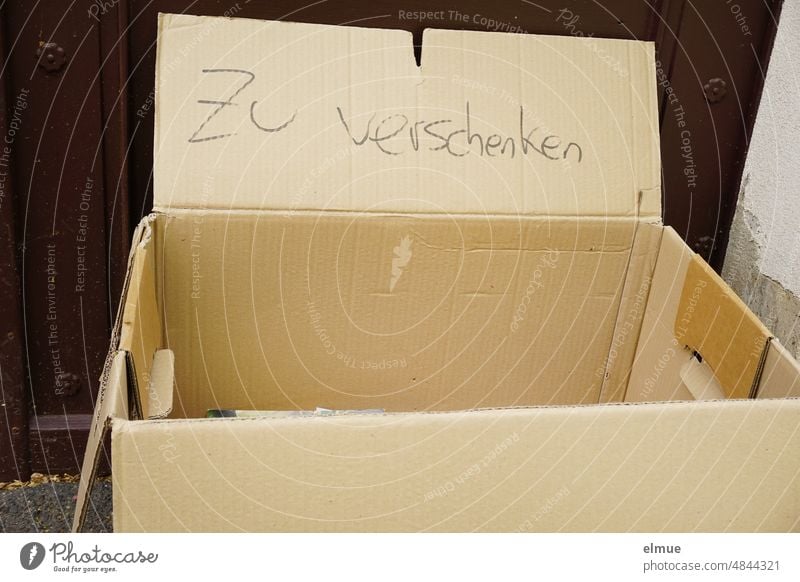 To give away - stands on a cardboard box in front of a front door / free / second hand to give away Cardboard Free-of-charge Donate Street Entrance needy Help