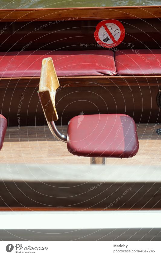 Single seat and red bench on a pleasure boat in sunshine for canal cruises in the old town of Bruges in West Flanders in Belgium Excursion boat ship Seat Chair