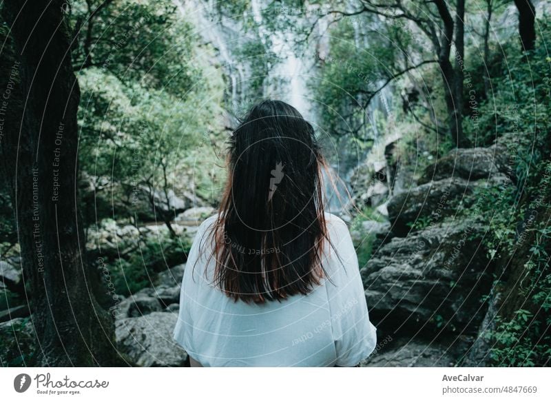 Young woman resting and looking a waterfall, freedom in nature, independent lifestyle and freedom concept. Natural parade and pure air concept. Copy space image