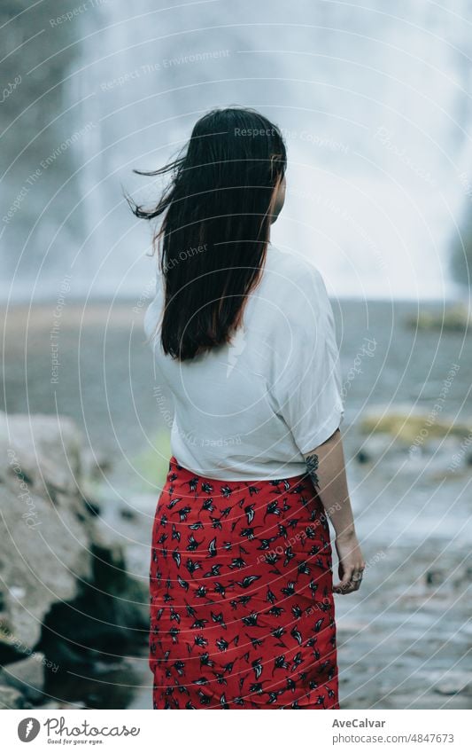 Young woman resting and looking a waterfall, meditation, yoga and thinking concepts. freedom in nature, independent lifestyle and freedom concept. Natural parade and pure air concept. Copy space image