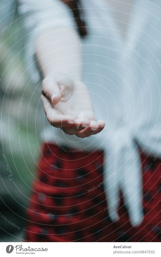 Woman giving one hand to the camera offering help on a natural parade, light image, help and self help concept, mental health.Therapy and looking for help,psychology and psychiatry concepts,copy space