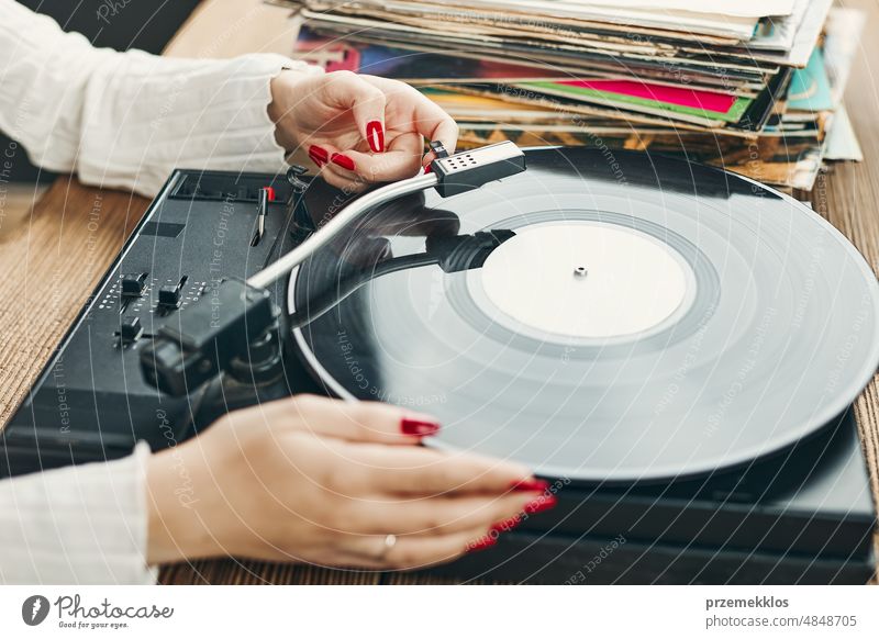 Young woman listening to music from vinyl record player. Playing music on turntable player. Female enjoying music from old record collection at home analog