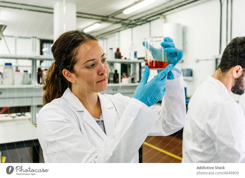 Serious chemist examining liquid in flask in lab woman scientist examine laboratory scientific chemical experiment sample test research expertise science focus