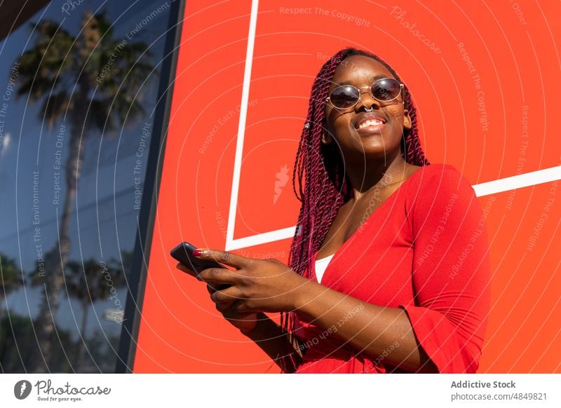 Cheerful black woman using smartphone female african american street happy mobile smile cheerful trendy style city gadget device urban sunglasses cellphone