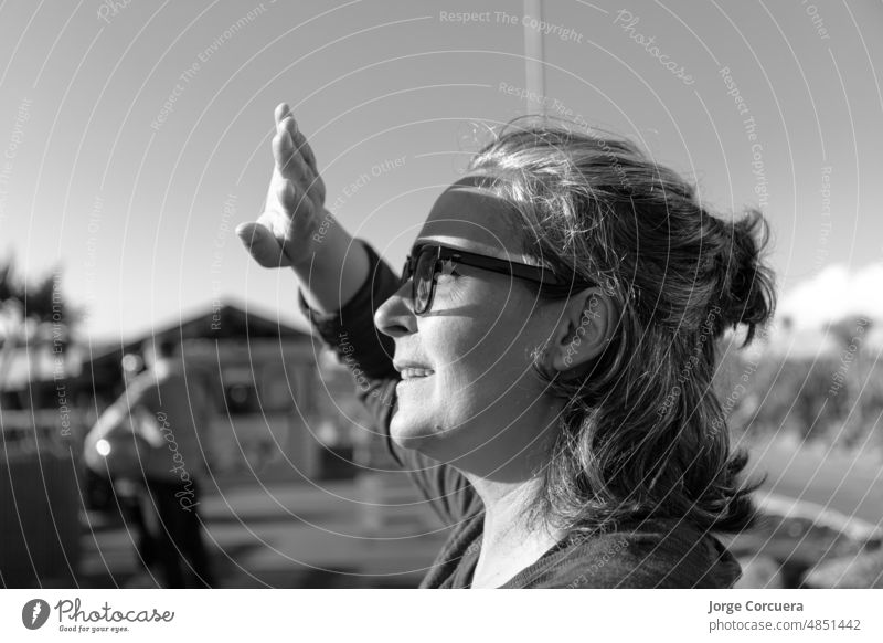 caucasican adult woman in an amusement park, looking at the sun and covering his hand causing shadows on his face. joy latin holiday posing female leisure