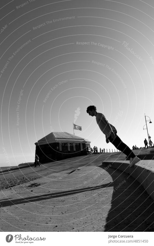 artistic portrait of a young teenager bending over and almost falling to the ground in monochrome casual lifestyle leisure joy outdoors creativity creative