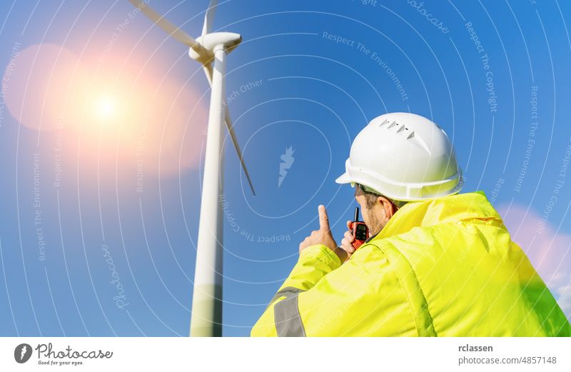 construction worker inspecting wind turbine, speaking with Walkie Talkie walky man helmet windmill inspection power communication building portable industrial