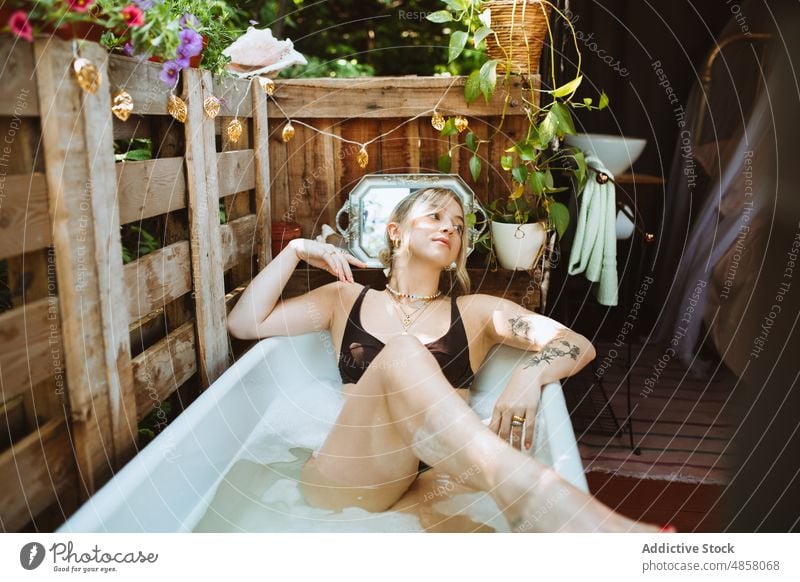 Woman in bath on patio woman bathtub water skin care terrace wellbeing chill routine style appearance feminine rest summer charming lady summertime female