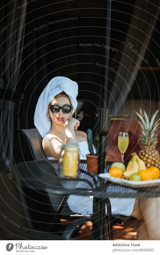 Woman in towels sitting on terrace woman morning patio literature hobby pastime serene leisure juice beverage drink feminine summer glass table female