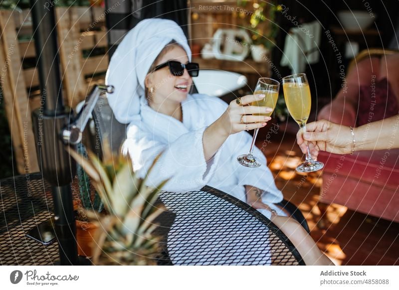 Woman in towel clinking glasses of juice with faceless person woman terrace patio morning toast beverage drink refreshment feminine leisure rest style summer