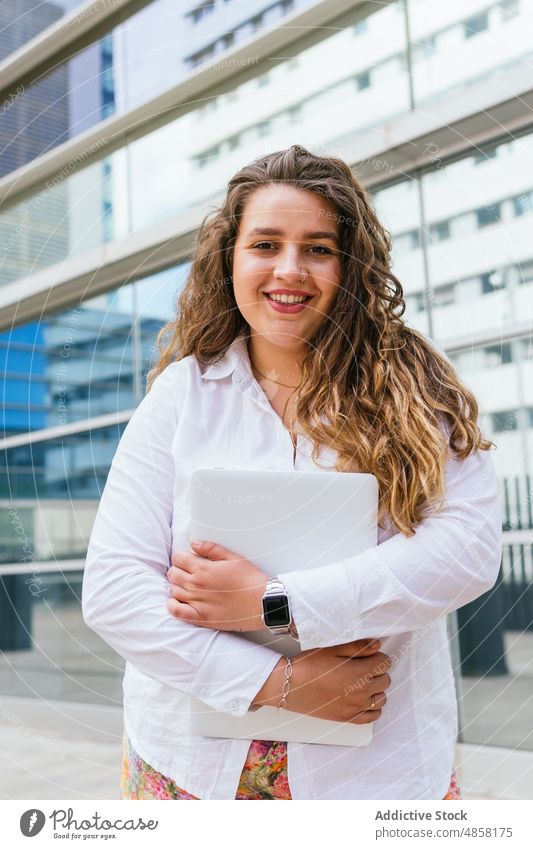 Cheerful woman with laptop looking at camera building urban street city appearance style surfing feminine female house glad modern wall town summer lady