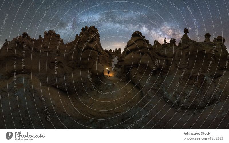 Anonymous traveler standing on stone on mountain with milky way on sky Goblin Valley canyon cliffs landscape night usa outdoors Utah nature State Park star