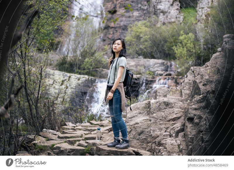 Asian hiker near waterfall in mountains woman travel rock adventure trekking photo camera photographer nature tourism valverde de los arroyos cascade