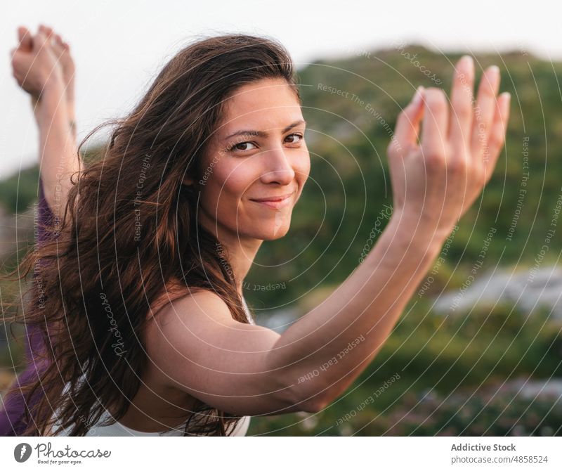 Delighted young lady standing in Dandayamana Dhanurasana yoga pose woman dandayamana dhanurasana standing bow smile mountain positive stress relief practice