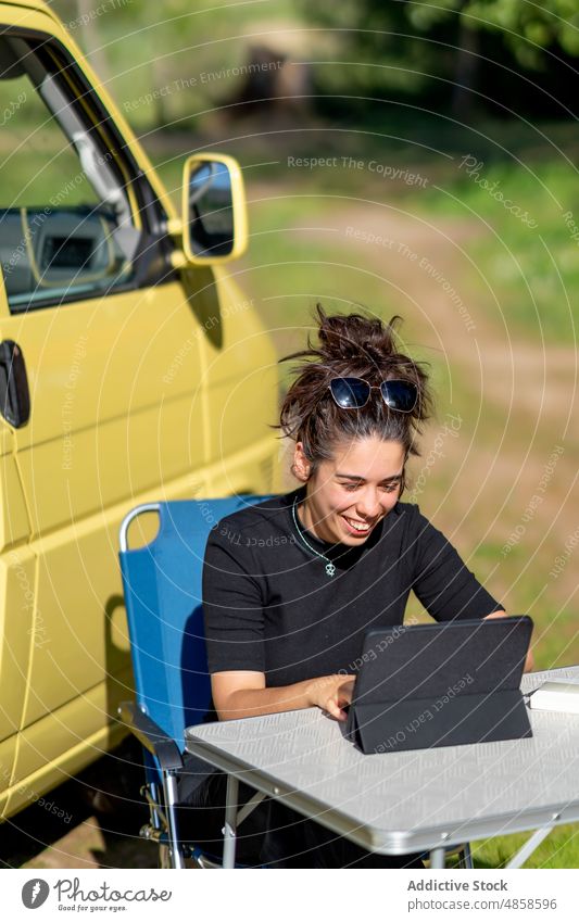 Hispanic woman using tablet outside camper countryside van smile data freelance weekend summer female hispanic ethnic daytime browsing device gadget happy