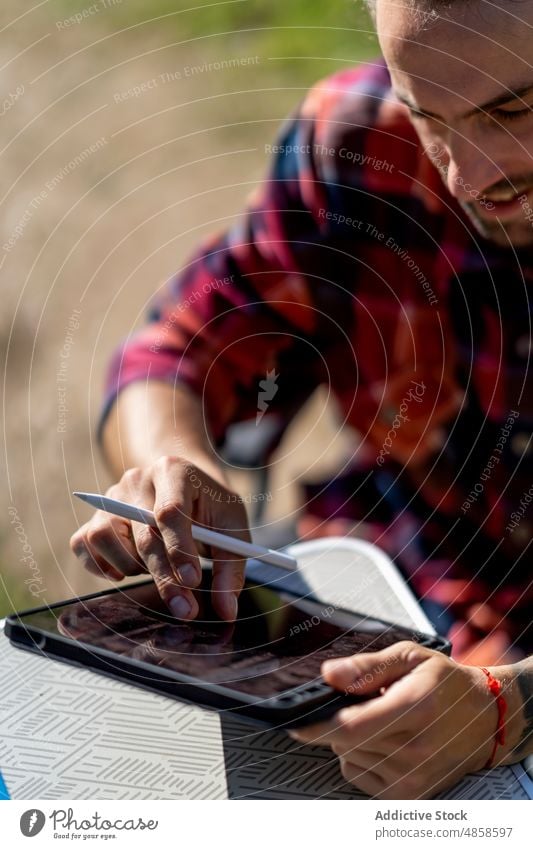 Ma using tablet outside camper man countryside van smile data freelance weekend summer daytime browsing device gadget happy online road trip chair positive