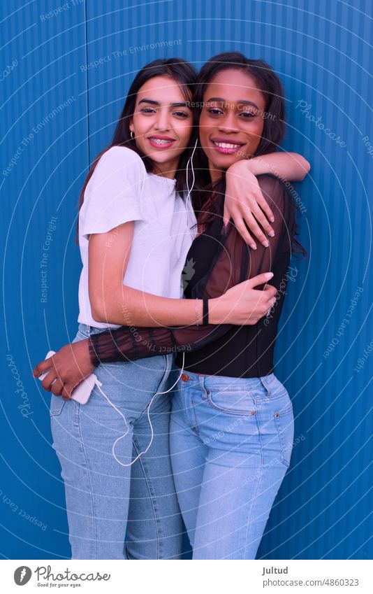 Two friends embrace each other in front of a blue wall. Girl Ethnicity spain Young Woman Twenties Trendy BuildingExterior Girlfriend Friendship Female Friends