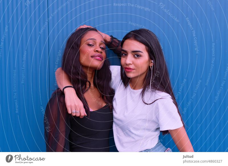 Two friends embrace each other in front of a blue wall. Girl Ethnicity spain Young Woman Twenties Trendy BuildingExterior Girlfriend Friendship Female Friends