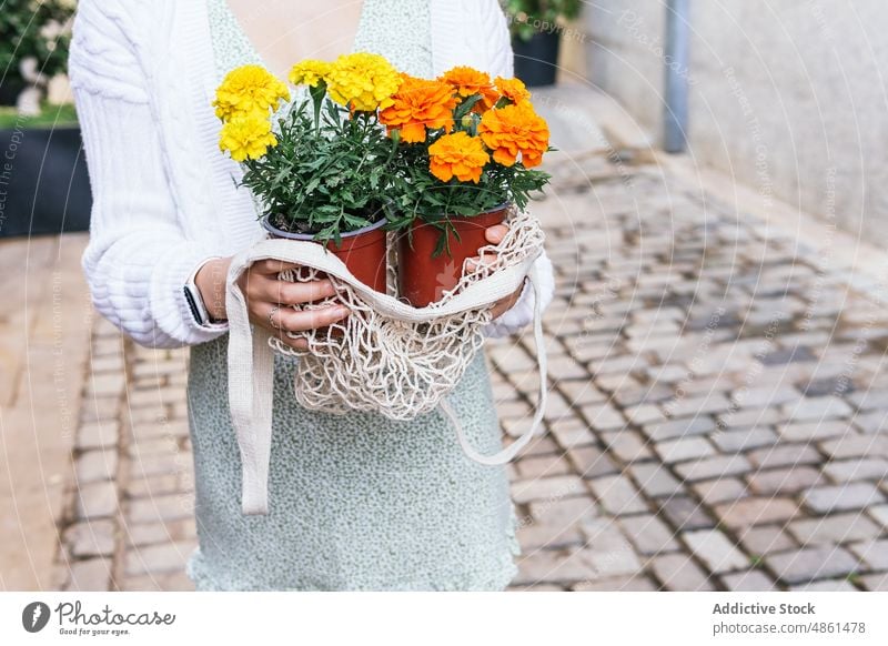 Woman with flowers in pots on the street woman marigold store floral flowerpot plant showcase city observe interest window customer potted female choice asian