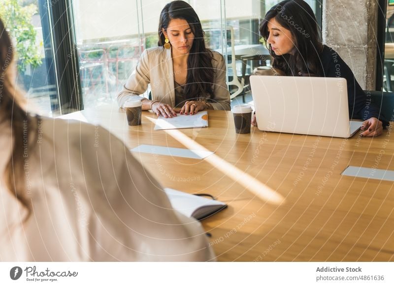 Happy Hispanic businesswomen discussing project in office meeting collaborate entrepreneur together smile colleague female brunette adult workplace table job