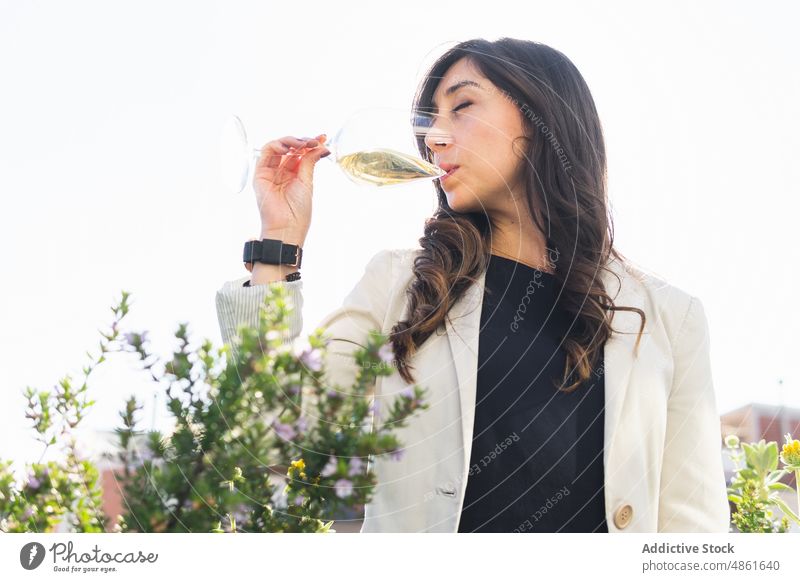 Female sommelier smelling wine on terrace woman degustate session summer drink white wine daytime weekend female adult brunette hispanic ethnic eyes closed