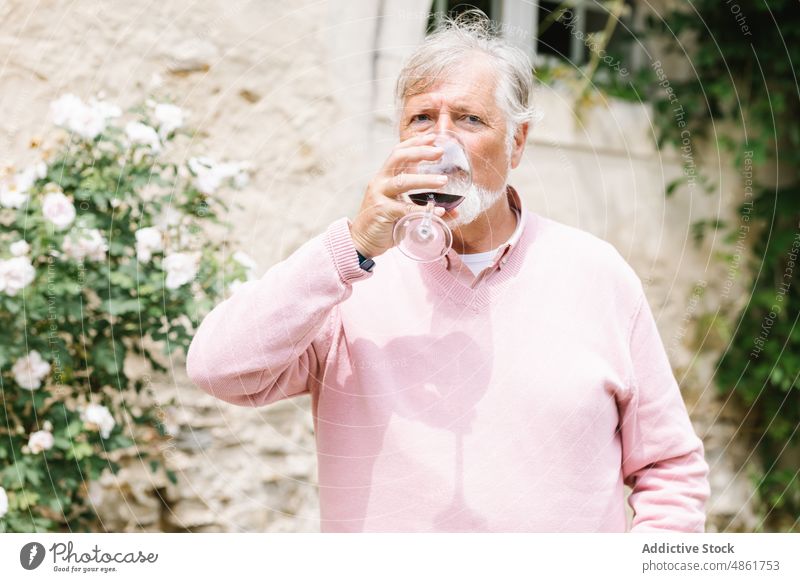 Mature man drinking wine during wedding celebration senior mature red wine alcohol celebrate event occasion festive beard party beverage elderly building street