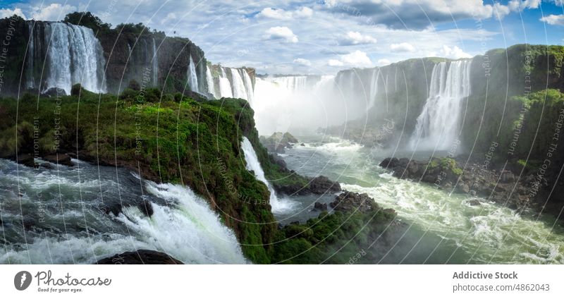 Amazing scenery of scenic waterfalls falling into fast river in sunlight landscape cliff nature range breathtaking picturesque rocky mountain spectacular