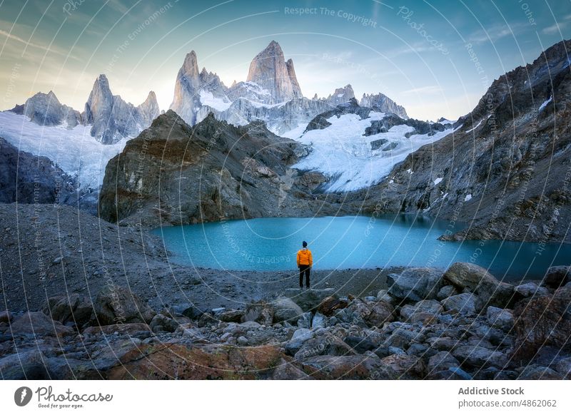 Anonymous traveler admiring alpine lake surrounded by rocky cliffs person admire mountain valley nature landscape picturesque wanderlust slope snow patagonia