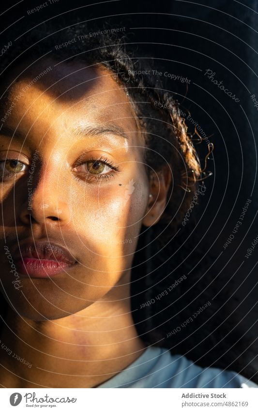 Thoughtful young ethnic woman looking at camera near window pensive calm dreamy sunlight thoughtful tranquil portrait contemplate serious alone female