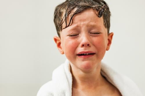 Sad boy with tears on face wrapped in white towel sad upset child eyes closed wet hair cry portrait problem kid unhappy depress frustrate expressive despair