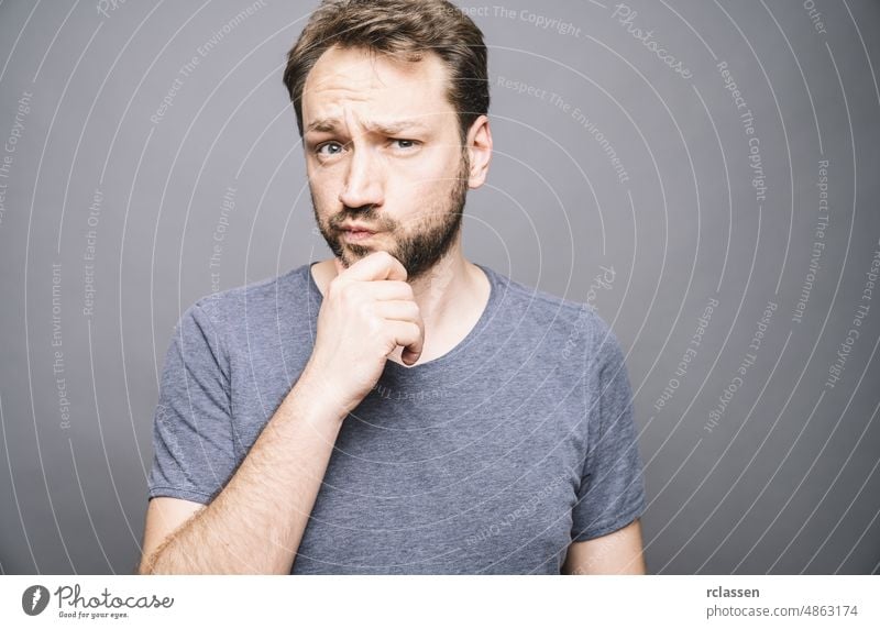 thoughtful man who looks away touching his chin and weighs the pluses and minuses of the offer face think hipster confused guy lost pensive gray business