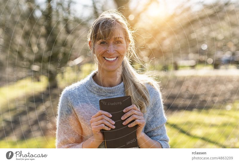 Portrait of a happy female student holding books and looking at camera outdoors girl mature college school campus university people young carrying woman