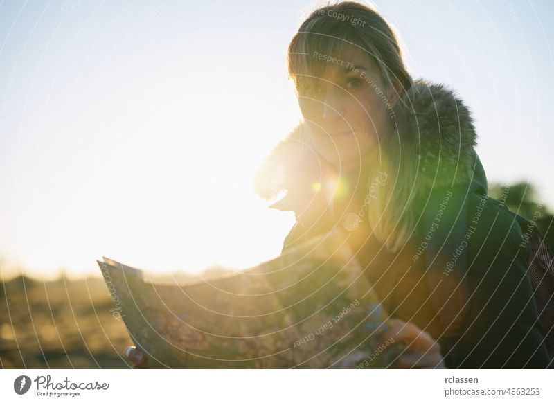 Woman hiker with a backpack and a map , searching right direction in the wilderness at sunset woman trekking beautiful orientation mountain nature adventure