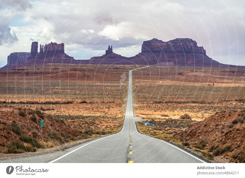 Scenic mountain in between asphalt highway cliffs utah Arizona national park landscape road Monument Valley roadway cloudy travel butte rocky outcrop