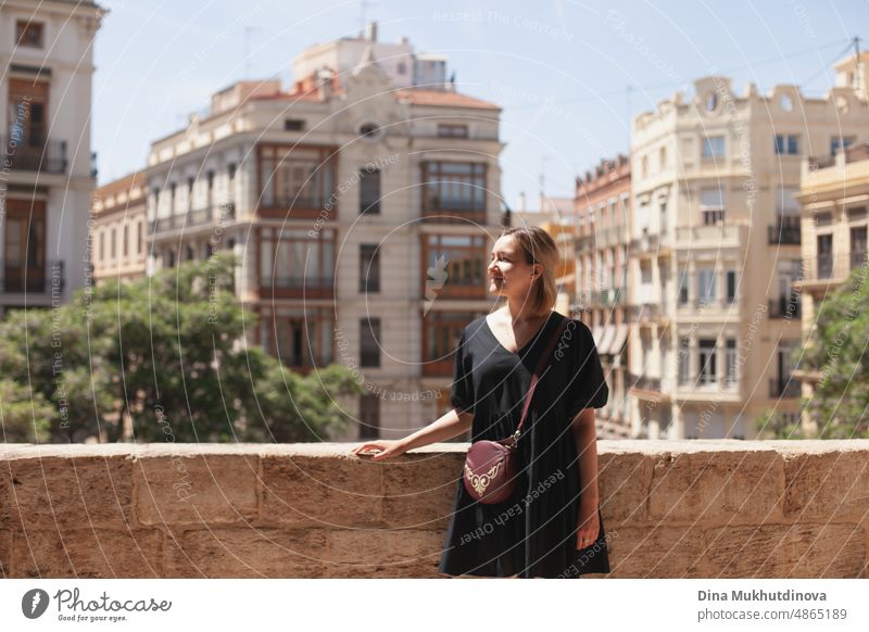 Young female tourist admiring the view of European city on sunny day. Woman sightseeing in summer on vacation. Heatwave in Europe affecting tourists and travelers.