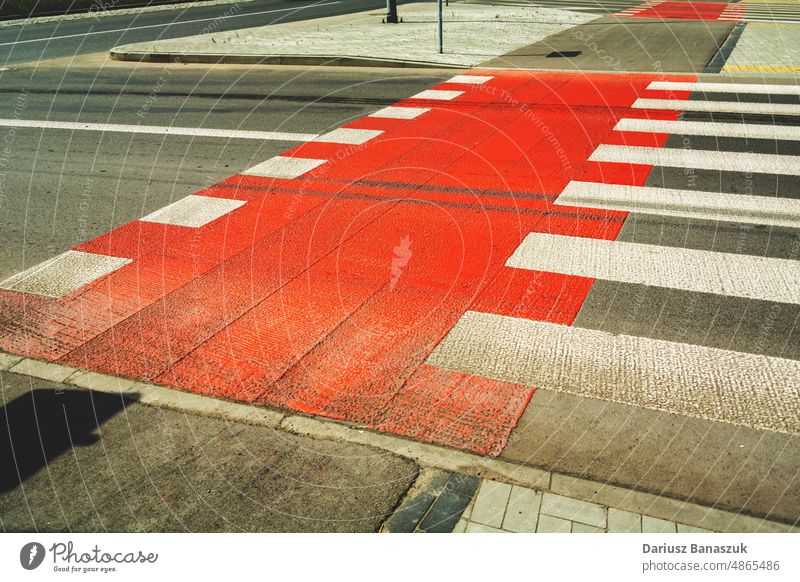 Red bike lane next to pedestrian crossing street road asphalt red bicycle city traffic white crosswalk sign outdoor path transportation way zebra urban symbol