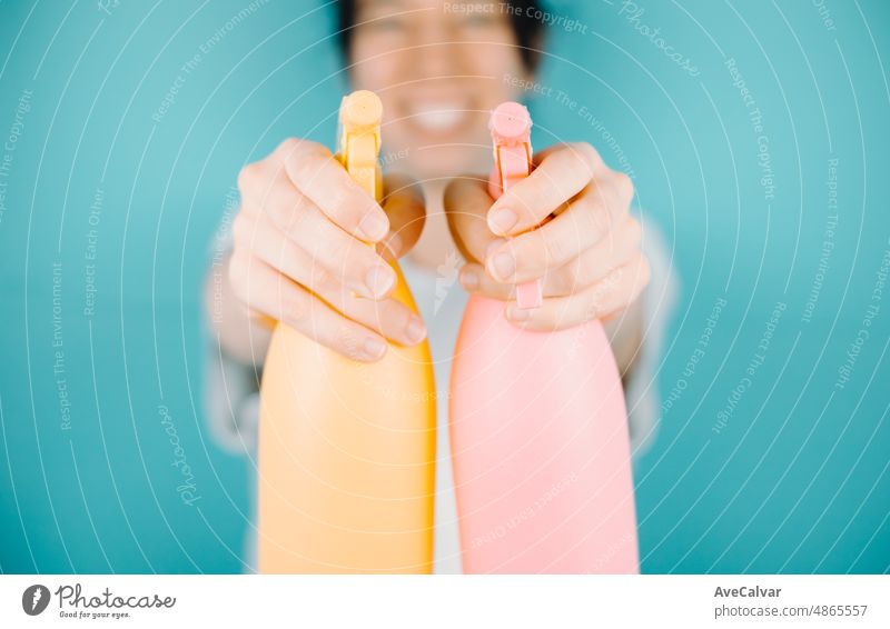 Young woman smiling happily to camera while aiming to camera a pair of water sprayer to refresh during summer. Holidays outdoors with copy space.Color background image