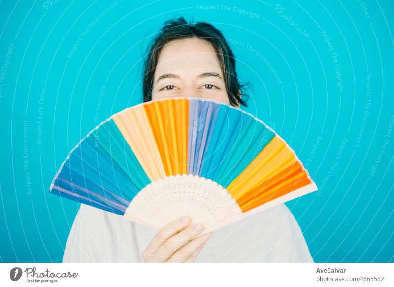 Woman smiling happily to camera while holding a LGBTIQ hand fan her showing pride. Lesbian woman, pride and fighting for her rights. Love is love concept. Color background image