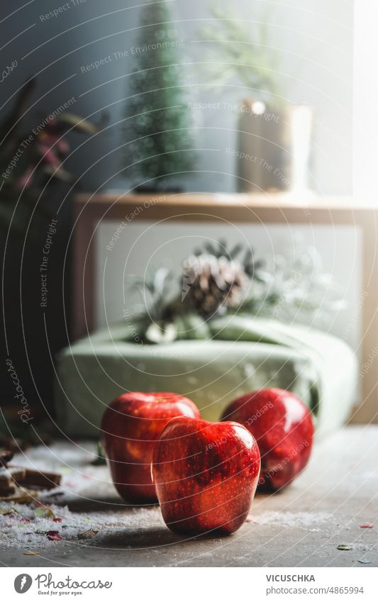 Three red apples on table with Christmas present and festive decorations background. three christmas present preparing sugar candied apples home sweet natural