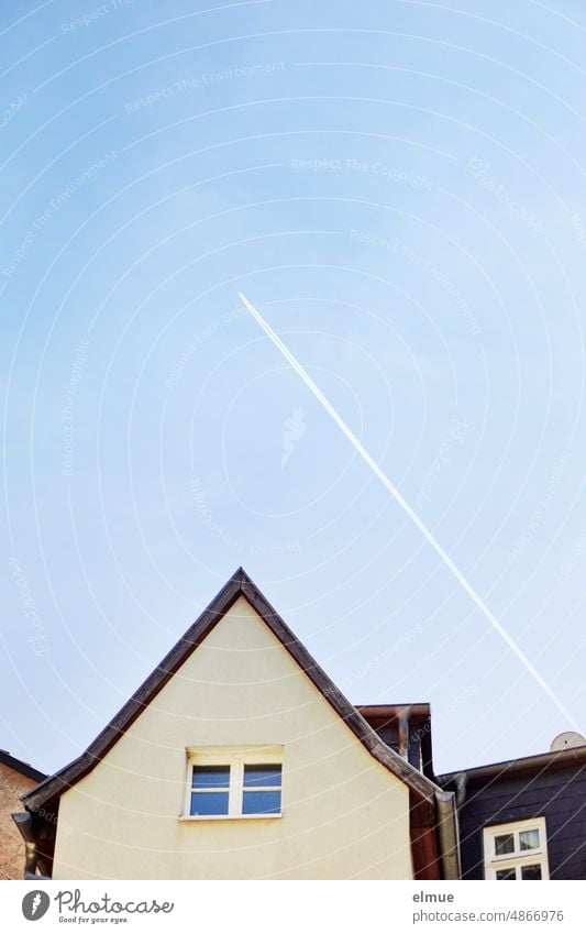 Condensation trails over the gable of a small apartment building / flyover / flight of thought Vapor trail flow of thoughts house gables pediment