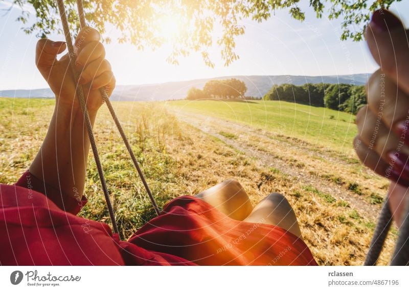 young woman on a swing. Point of view shot. pov carefree girl nature relax freedom perspective red blond lifestyle harmony summer motion wind happy eifel