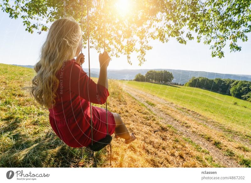 beautiful young woman on a swing on summer day outdoors girl blond tree person cloud park female fly eifel red adult joy activity beauty blue caucasian cheerful