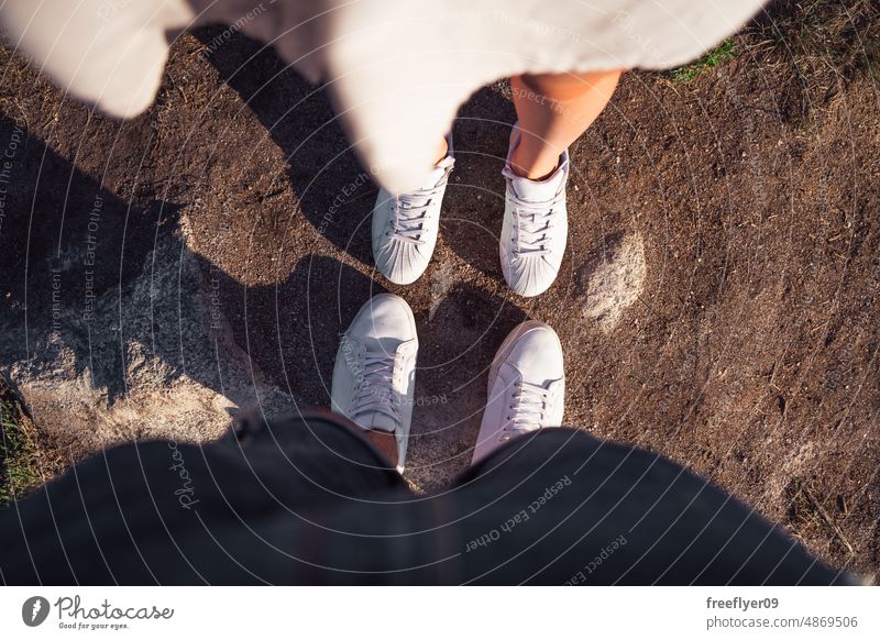 Feet of an heterosexual couple looking at each other feet love young sneakers from above POV person male culture wear modern youth foot directing female shoe