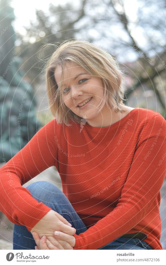 likeable young blonde woman in orange sweater smiles Woman youthful Blonde Smiling Congenial naturally Authentic portrait Happiness Attractive Contentment